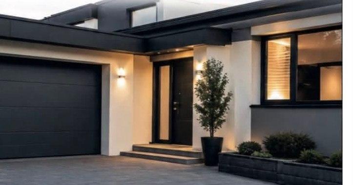 Porte de garage sectionnelle anthracite sur une maison moderne, éclairée au crépuscule