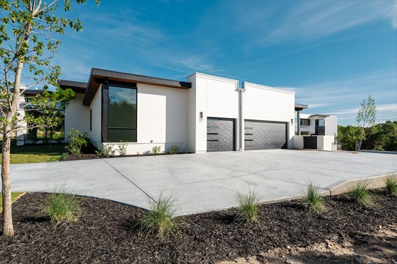Maison blanche moderne avec deux portes de garage et allée en béton