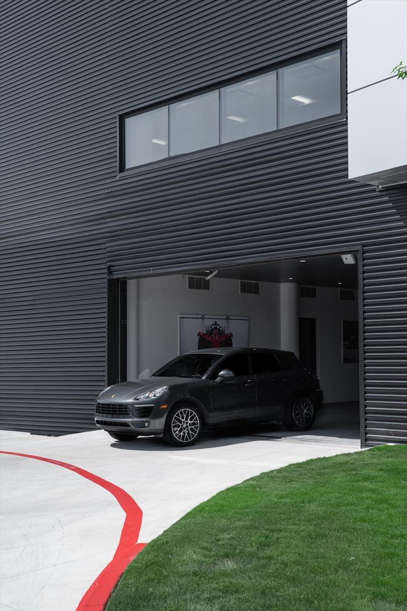 Grande porte de garage motorisée ouverte sur un bâtiment à façade sombre